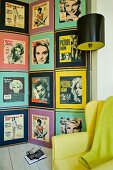 Wandgestaltung mit Sammlung von Frauenpotraits aus den Fifties hinter Retro-Stehlampe und gelbem Sessel
