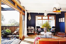Blau getönter Wohnraum mit Couchtisch, teilweise sichtbarem Sofa & offener Schiebetür zur Terrasse