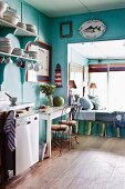 Vintage kitchen painted turquoise with daybed in window niche and maritime decorations on wall