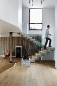 Open-plan stairwell in contemporary house with sculpture on plinth in front of staircase and man walking up stairs