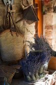 Bunches of dried lavender in wire basket in front of shopping bag hanging on rustic wall