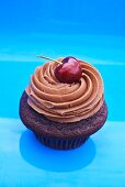 A cupcake topped with chocolate buttercream and a cherry