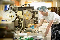 A worker in a bakery operating the packaging machine