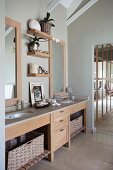 Long washstand with solid wood base unit and storage baskets in open-plan bathroom
