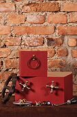 Stacked, rust red boxes with attached components against rustic brick wall