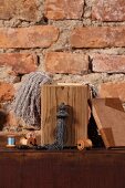 Wooden box and haberdashery items on chest of drawers against rustic brick wall