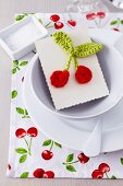 Cherry-patterned place mat and card with crocheted cherries as guest favour