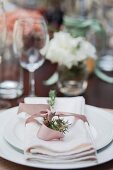 A white place setting decorated with a bow and herbs