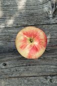 An apple on a wooden table in the garden (view from above)