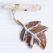 Brown leaf hanging from birch twig as pendant