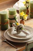Pussy willow napkin ring on place setting with green candles and Easter arrangements on table