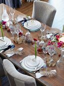 Gedeckter Tisch für Weihnachtsessen mit Blüten, Federn, Nüssen und Dekokugeln
