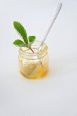 A jam jar with the remains of apricot jam and a spoon