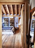 View through open door into rustic bedroom with wooden floor
