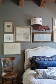 Scatter cushions on French bed with curved headboard below framed pictures on pale grey wall