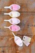 A row of marshmallows in spoons, on a wooden surface