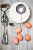 An old rotary hand whisk, eggs and sugar