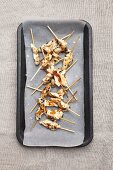 Satay skewers on a baking tray
