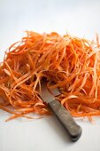 A mound of carrot peelings with a knife