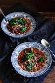 Two plates of vegetables soup with black beans, salsiccia and green kale