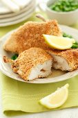 Breaded chicken escalope with butter, lemon wedges and peas
