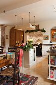 Dining area with wrapped presents in front of free-standing counter below suspended, overhead lighting unit in open-plan, country-house kitchen