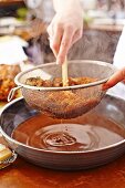 Lamb gravy being strained through a sieve