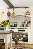 Country-house kitchen with masonry hob area decorated with nostalgic copper pots and pans
