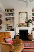 Living room with open fireplace, bookshelves and nostalgic velvet armchair on Moroccan rug