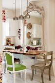 Various antique chairs around vintage dining table in front of ornate mirror above bench