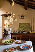 Country-house ambiance with decorative pendant lamp and painted crockery in open-plan living area