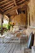 Vase of sunflowers on combined table and benches on rustic veranda with wooden floor