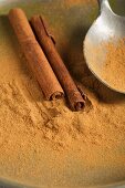 Ground cinnamon and cinnamon sticks, with a spoon