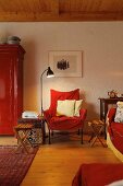 Seating area in shades of red with chair, sofa & cupboard in village house (Eggelingen, Ostfriesland, Germany)