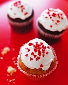 Cupcakes with cream frosting and red heart sprinkles