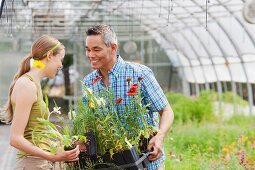 Mann und Frau mit verschiedenen Blumen in Kunststoff Töpfen im Gartencenter