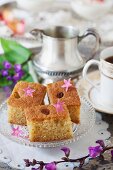 Samolina cake on a silver tray with cup of coffee and flowers