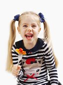 A small girl holding a fork with pasta and tomato