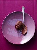 A quenelle of chocolate mousse on a purple plate with a spoon