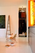 Modern living area with cloakroom niche and orange light installation above grey sideboard