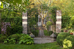 Vintage house concealed behind tall, closed garden gate and green front garden