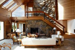 Open-plan, two-storey interior with modern wood panelling and staircase against stone-clad chimney breast