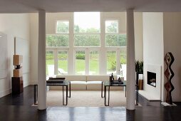 Objet d'art, white sofa and open fireplace in interior with postmodern glass wall