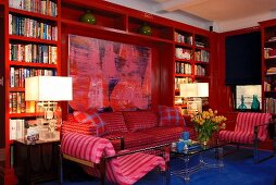 Red bookcase in modern living room with large painting and blue floor