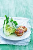 Lettuce with grated cheese, a yoghurt dressing and toasted baguette topped with bacon