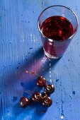 Cherries and cherry juice on a blue wooden tabletop