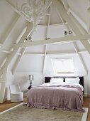 Tower room with double bed under skylight; bedside lamp with silver lampshade on bedside table