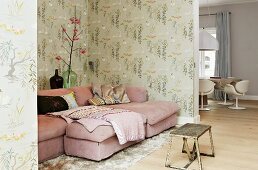 Pink couch and retro wallpaper in living area; vintage table in foreground