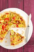 Quiche with leek, peppers and ham, partly sliced