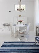 Swedish-style dining room in white & blue with set table & chandelier